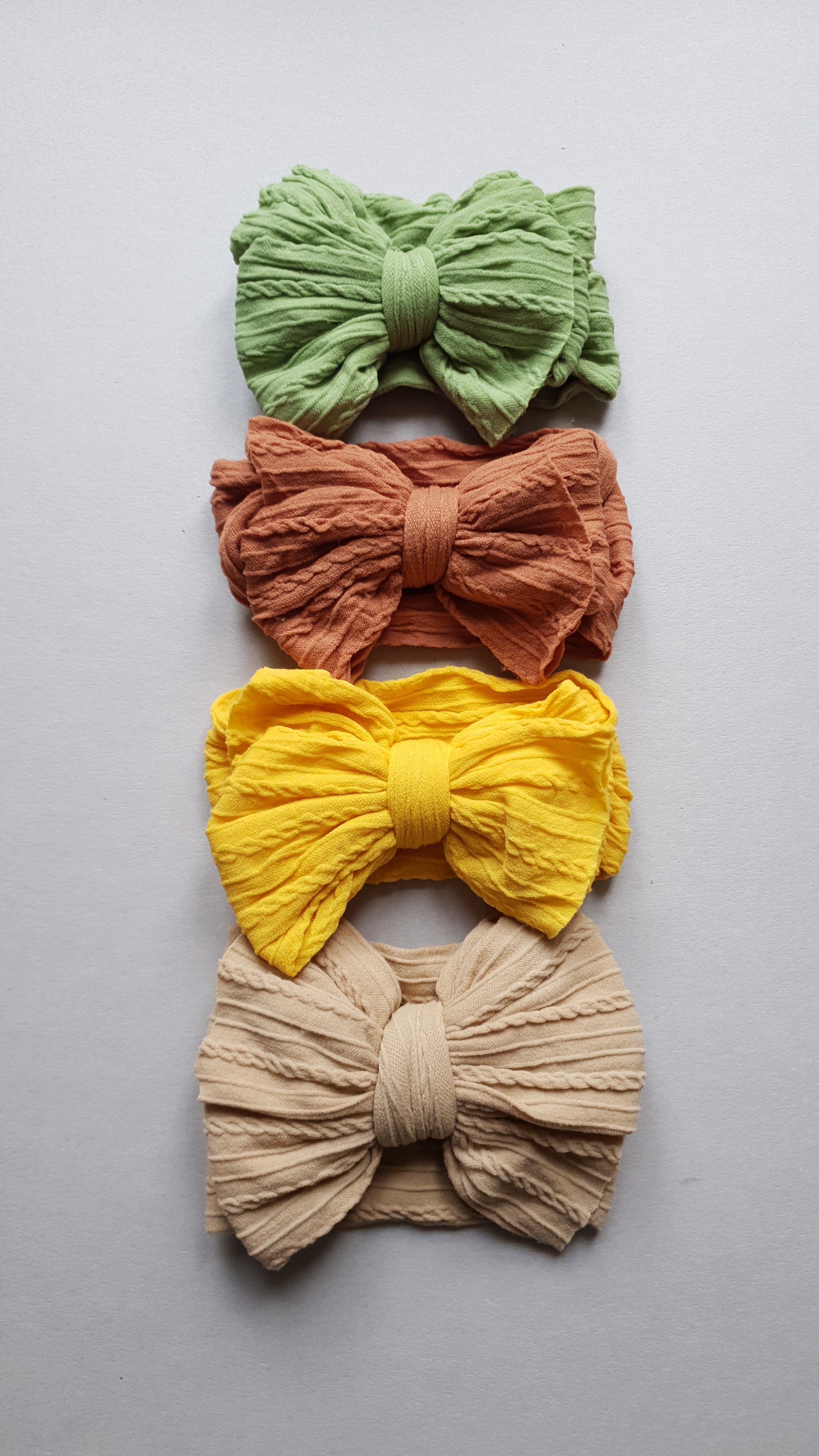 Four textured fabric bows on a light gray background