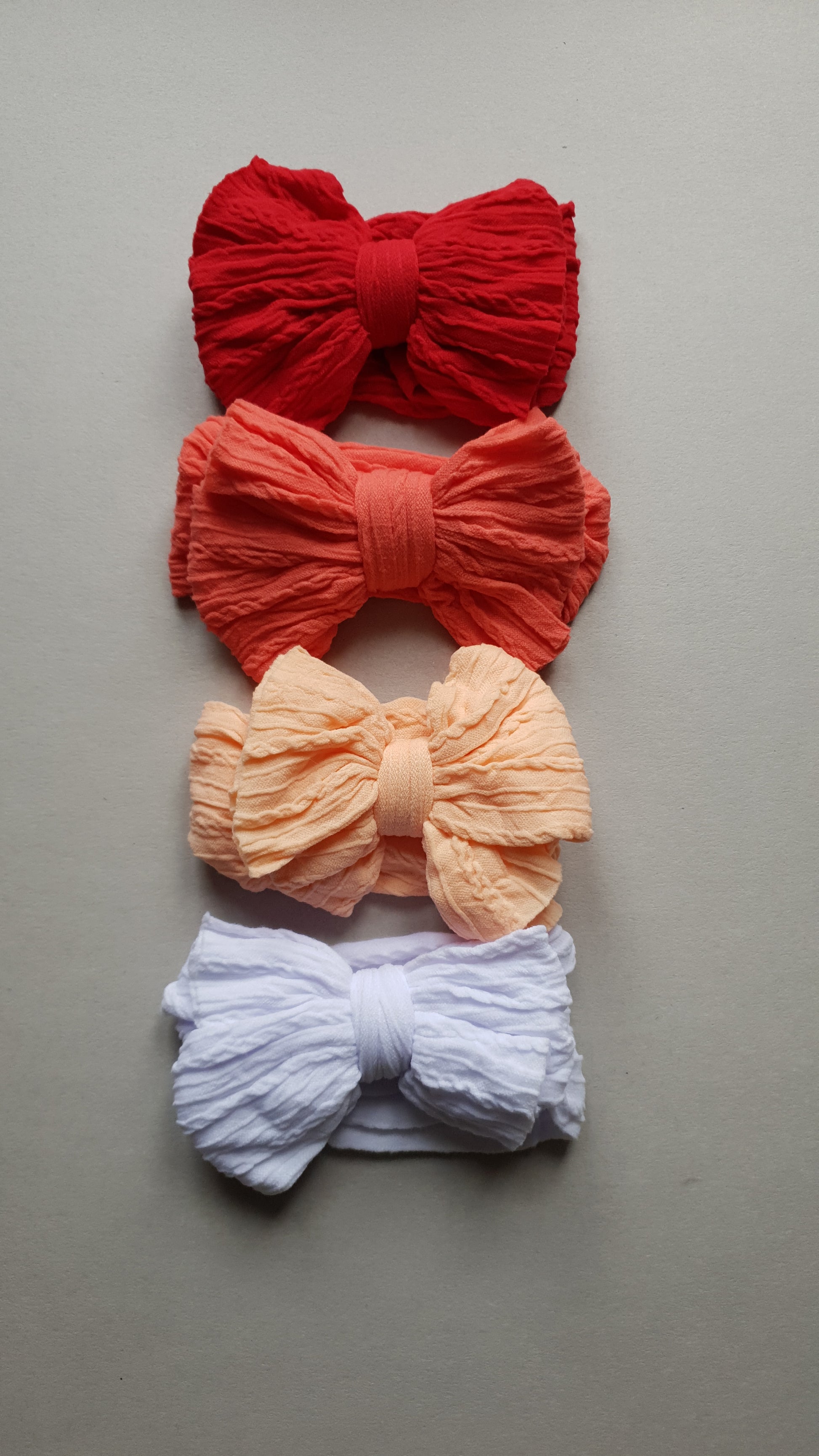 Textured bows stacked vertically on a neutral background.