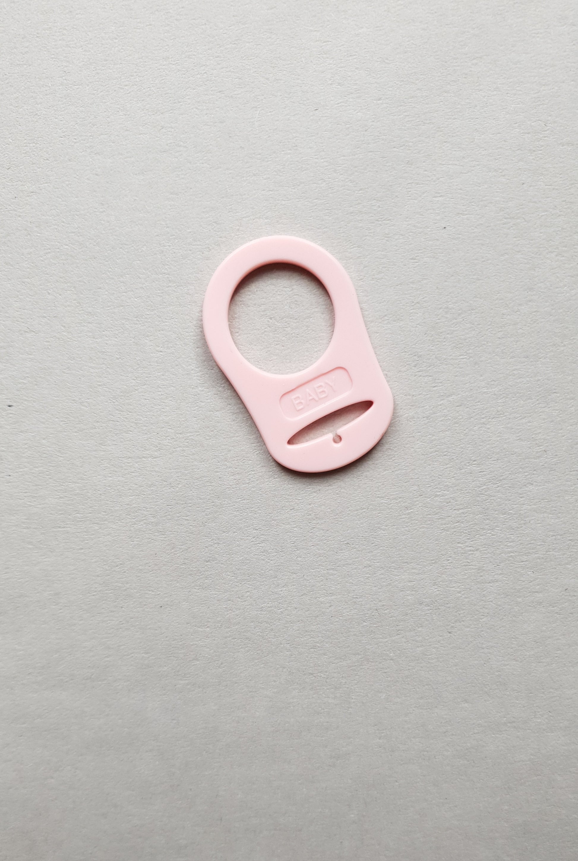 A small pink plastic object with the label BABY.