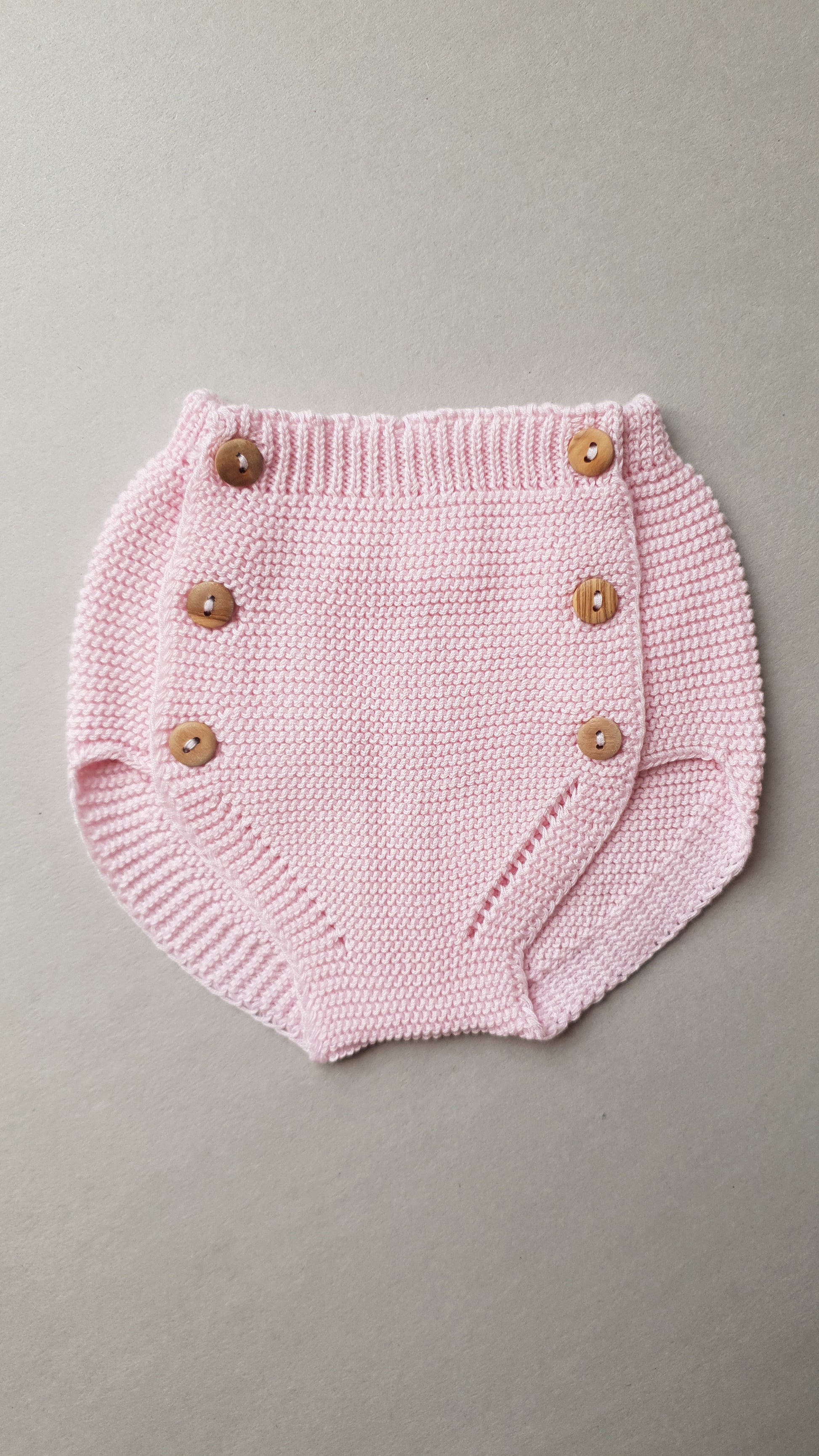 A pink baby diaper cover with a ribbed waistband.