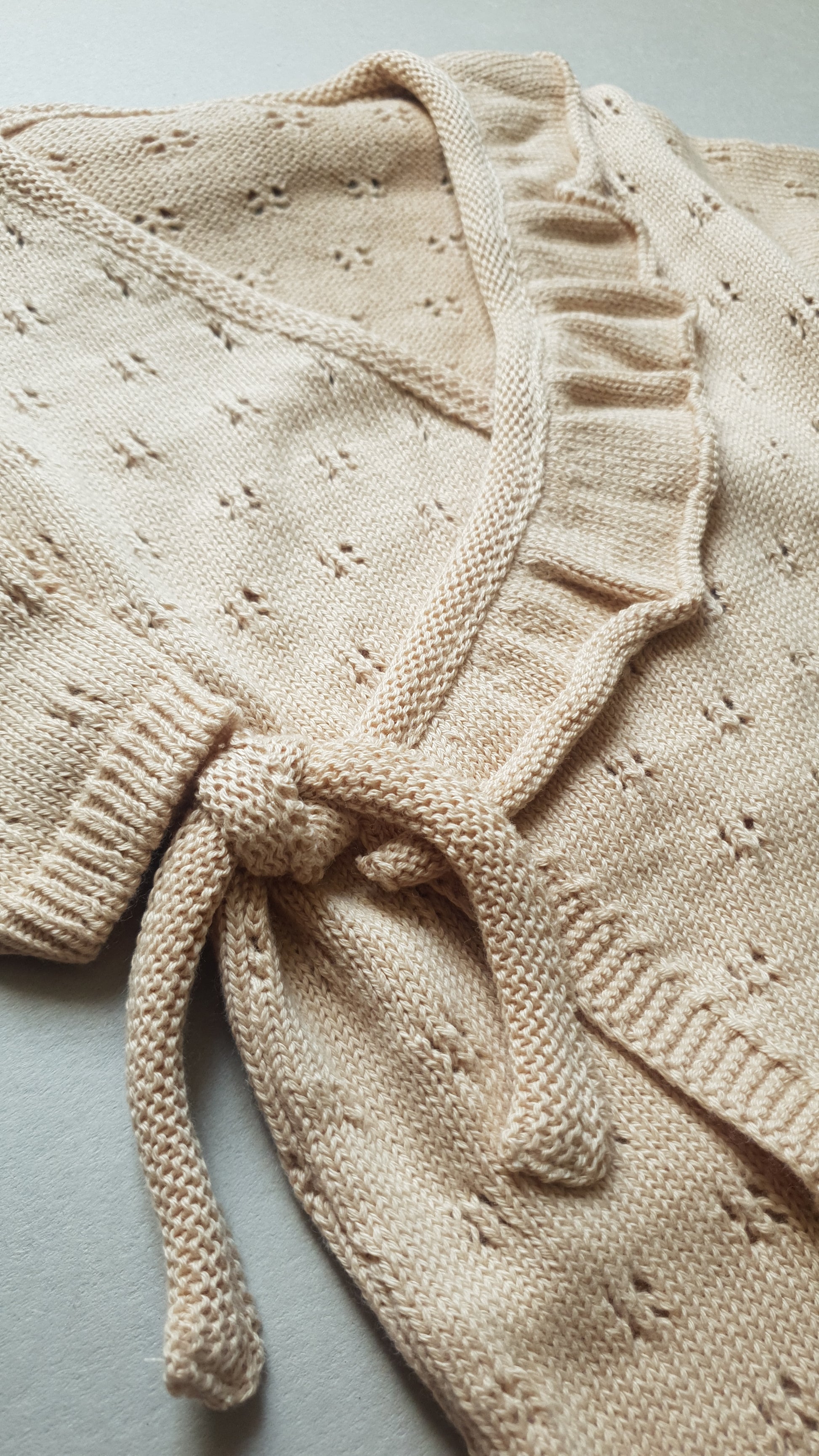 Cream knit cardigan with delicate lace details.