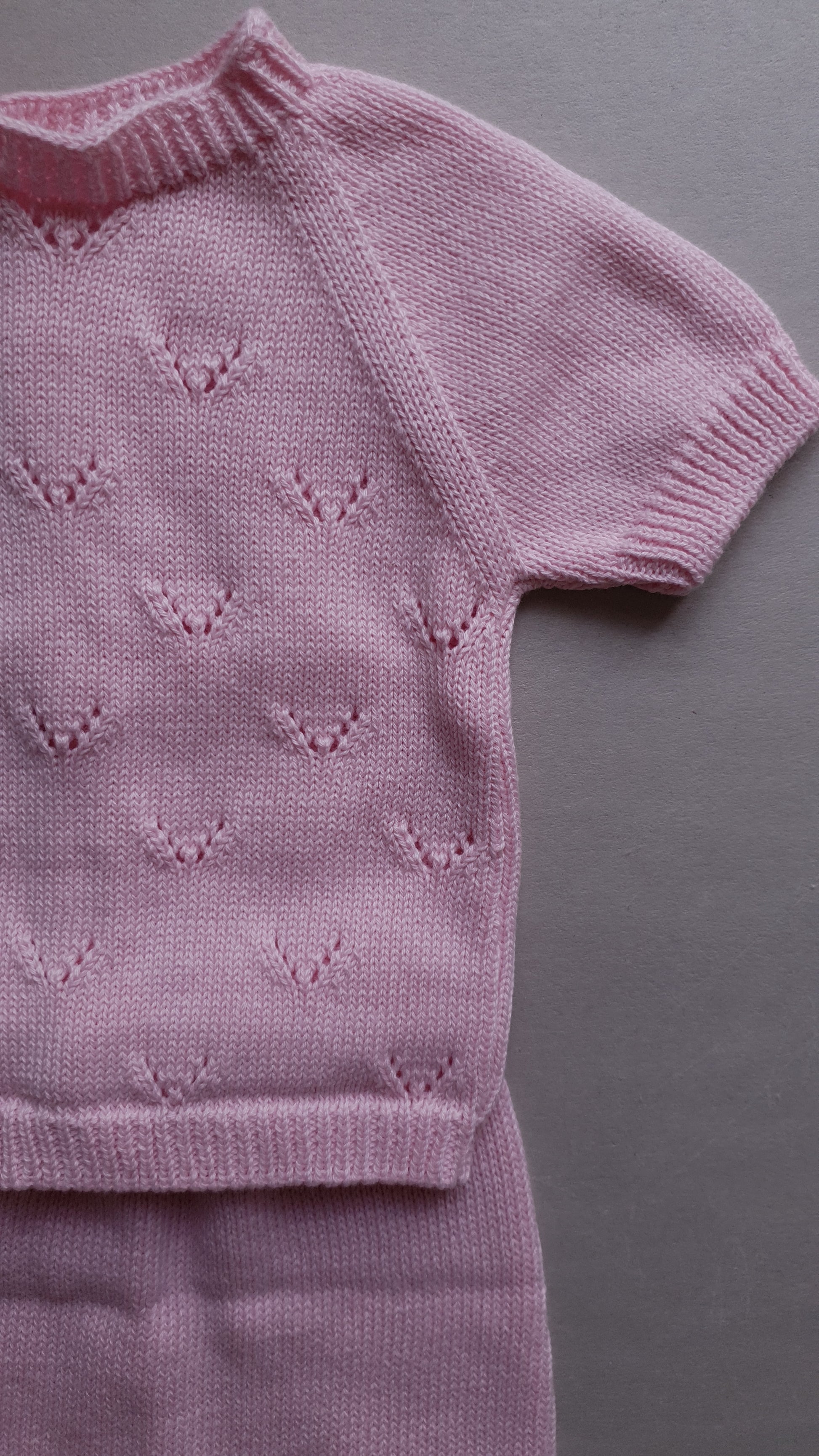 Pink baby outfit with short sleeves and a heart pattern.