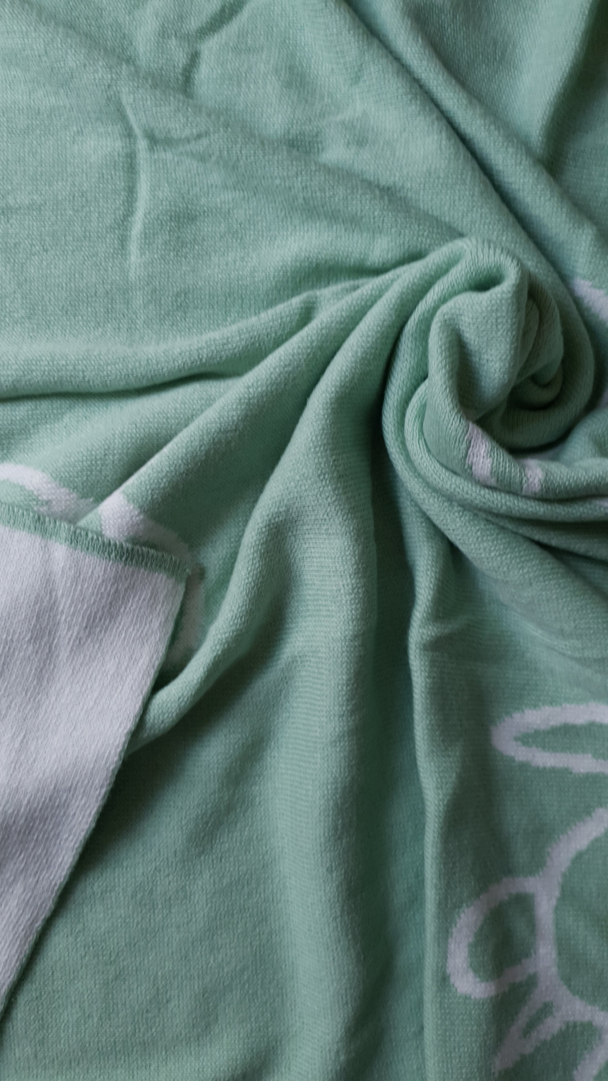 A mint blanket with a spiral pattern and a white border.