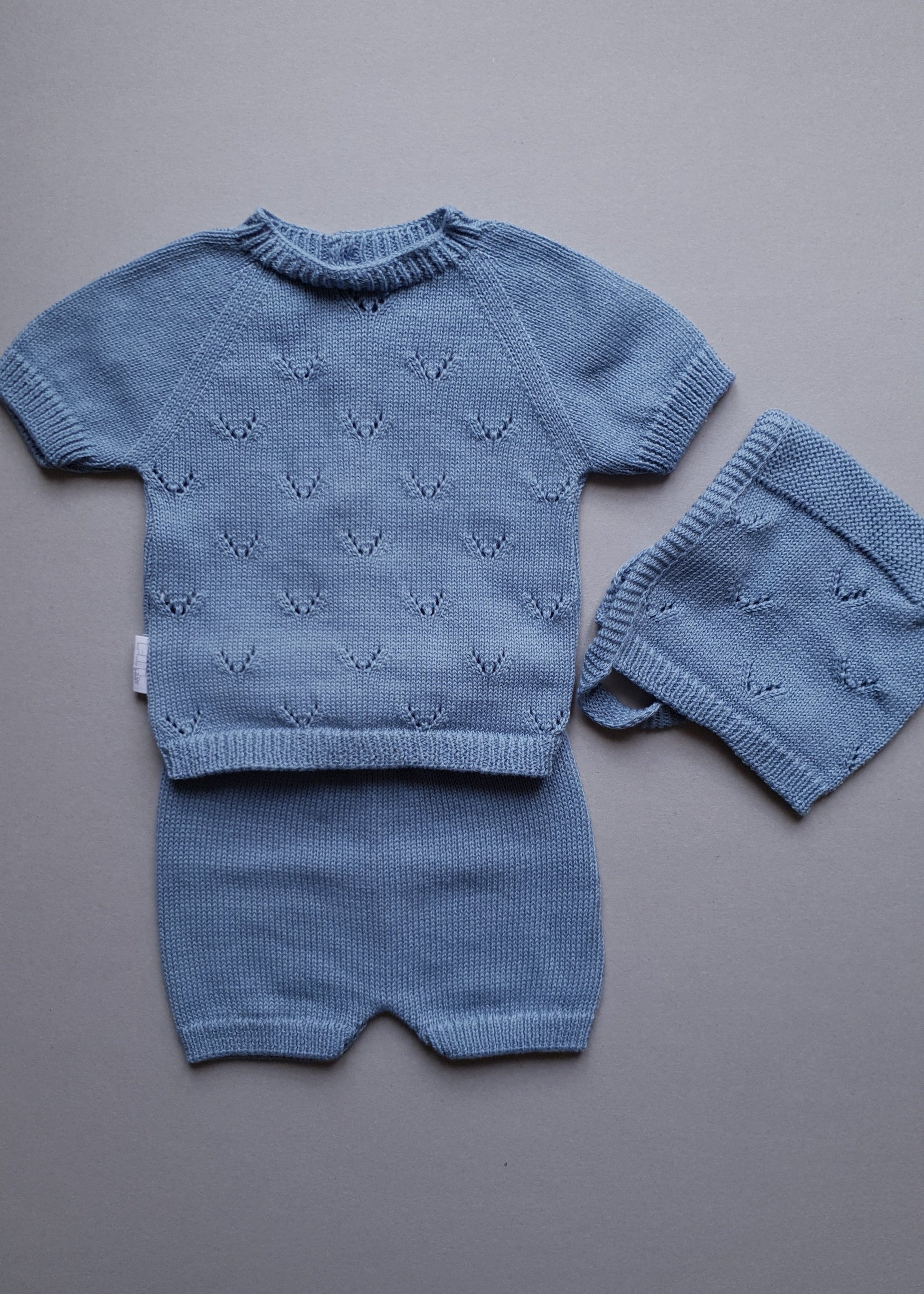 Blue knitted baby outfit with short-sleeve top and shorts.