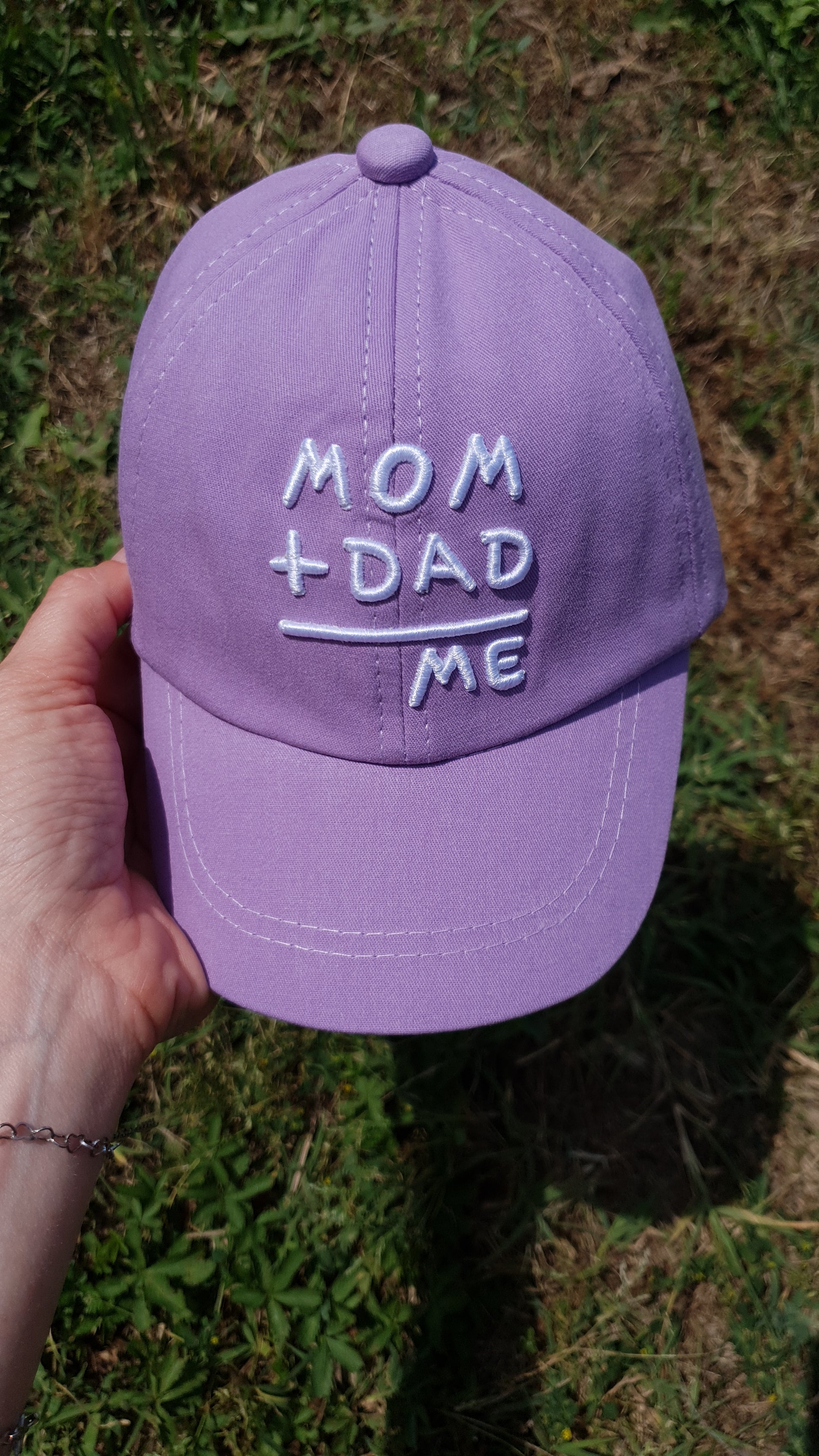 A purple baseball cap with the MOM + DAD = ME message.