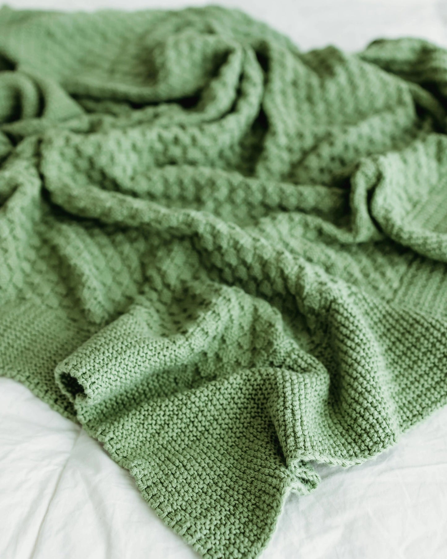 A cozy, textured green knitted blanket with a waffle pattern.