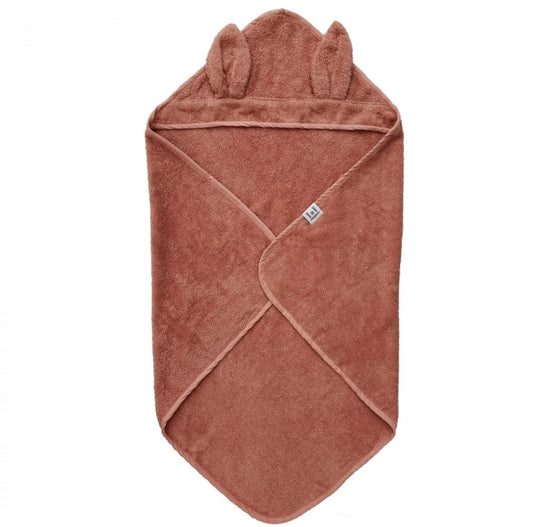 A brown baby towel is folded with two ears on the hood.