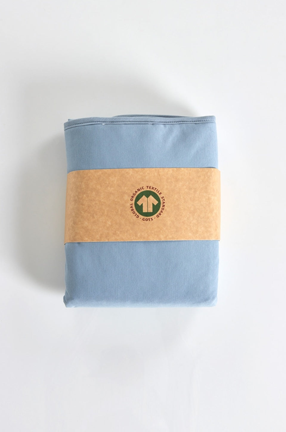 Folded blue fabric wrapped in brown paper with GOTS logo