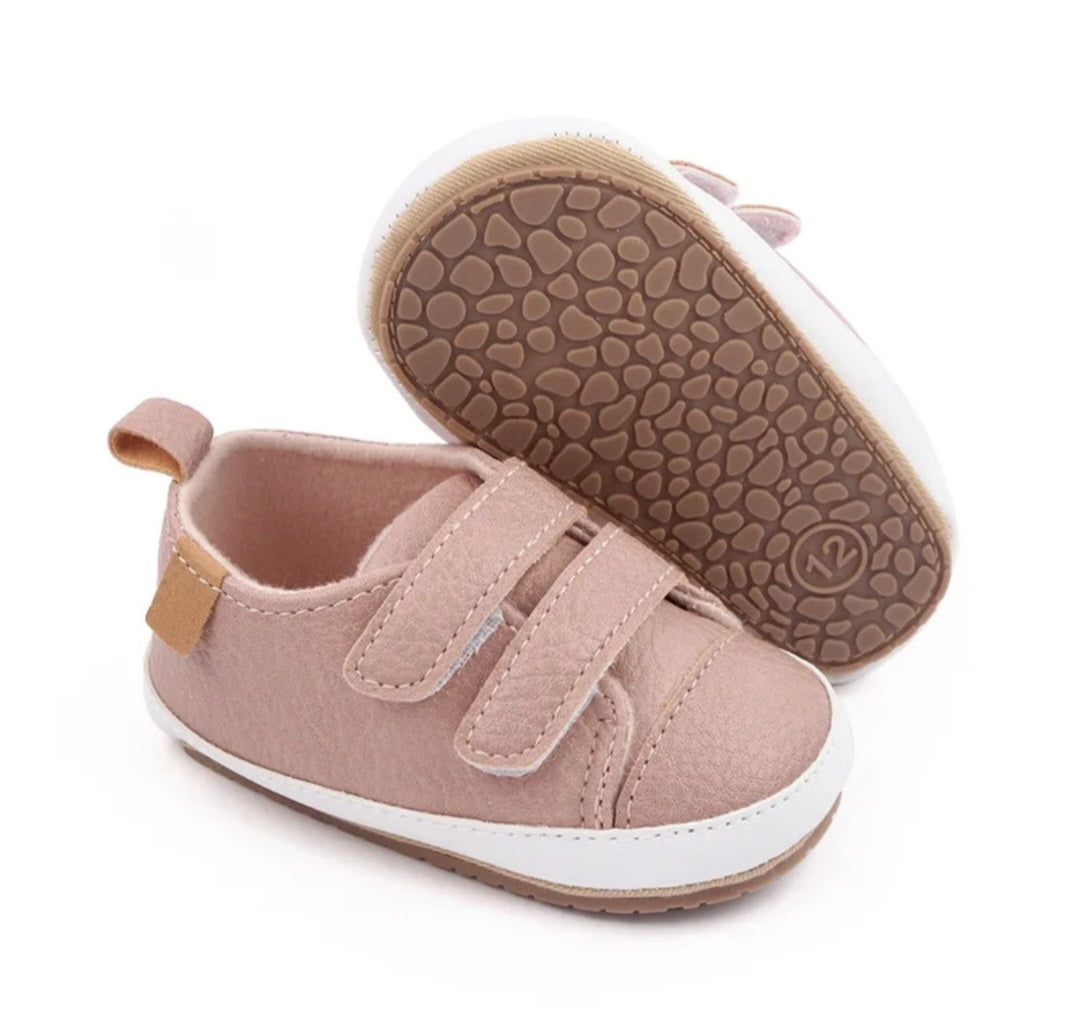 Soft pink baby shoes with velcro straps and a brown sole.