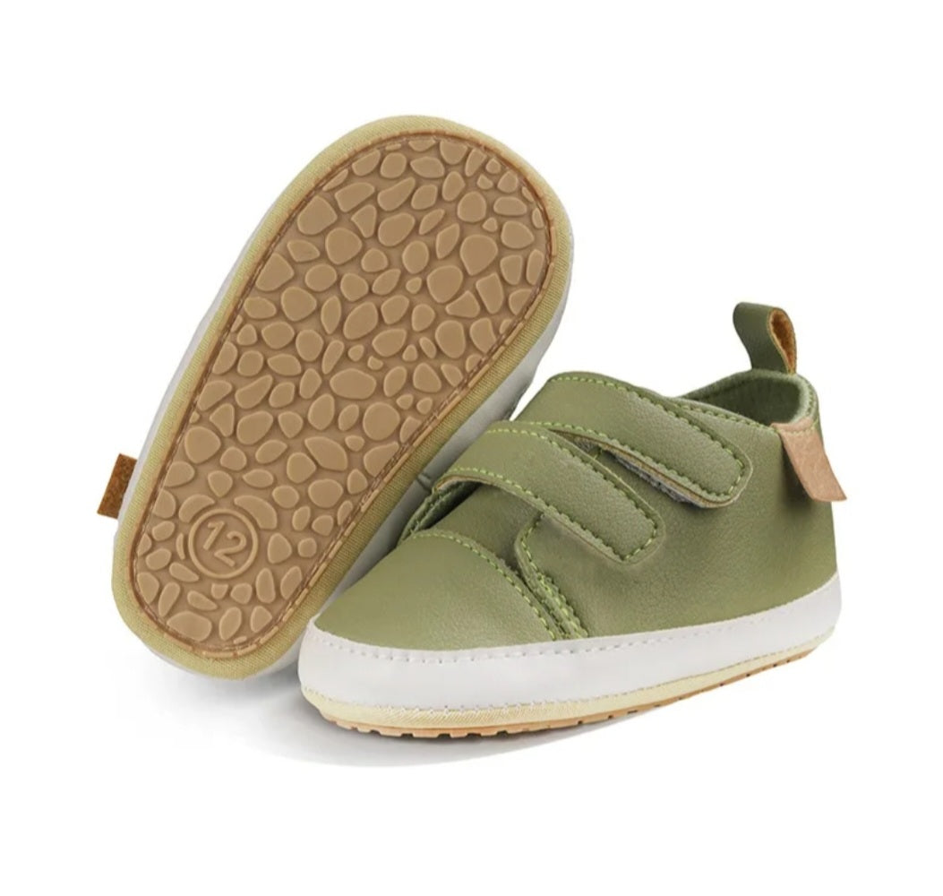 A pair of olive green baby shoes with beige soles.
