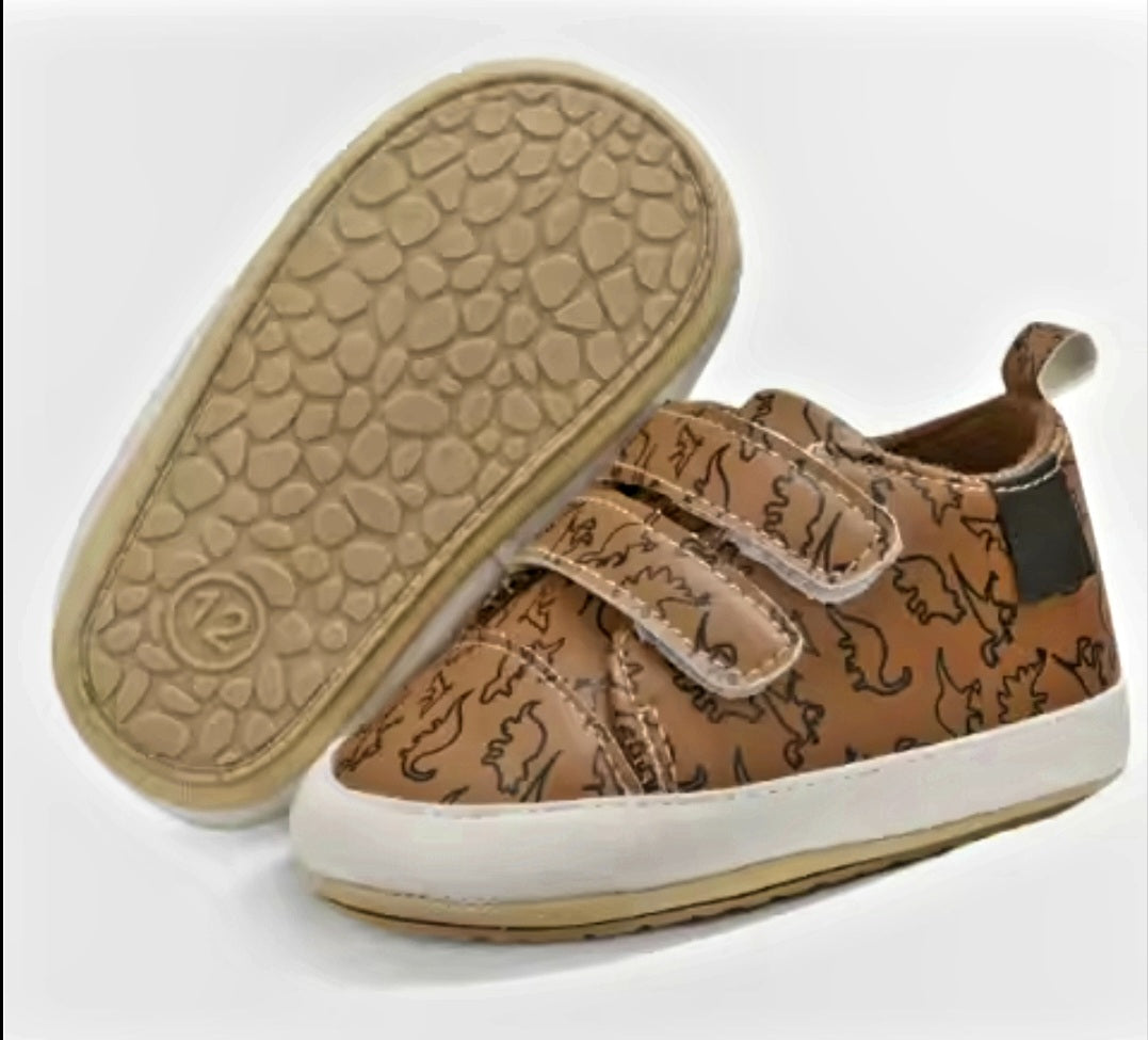 Brown toddler shoes with dinosaur print and Velcro straps.