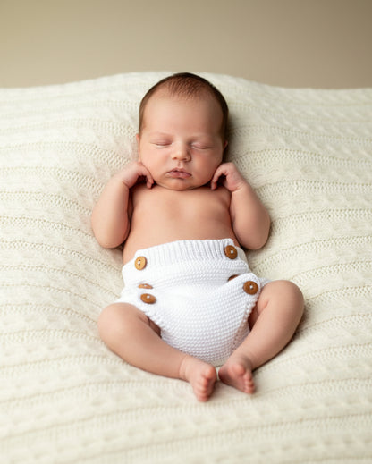 White knitted baby bloomers with wooden buttons.