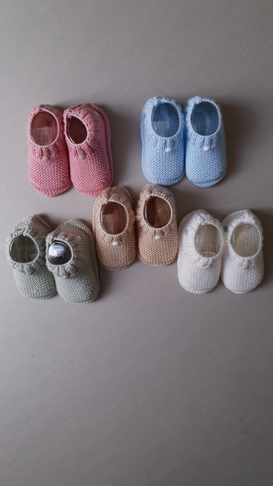 Five pairs of knitted baby booties in pastel colors.