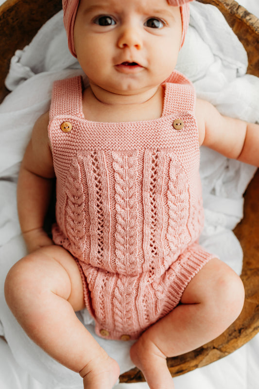 Baby in a pink knit outfit and a matching headband.